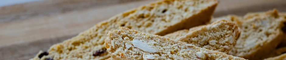 Pieces of almond cranberry biscotti laying on a wooden cutting board.